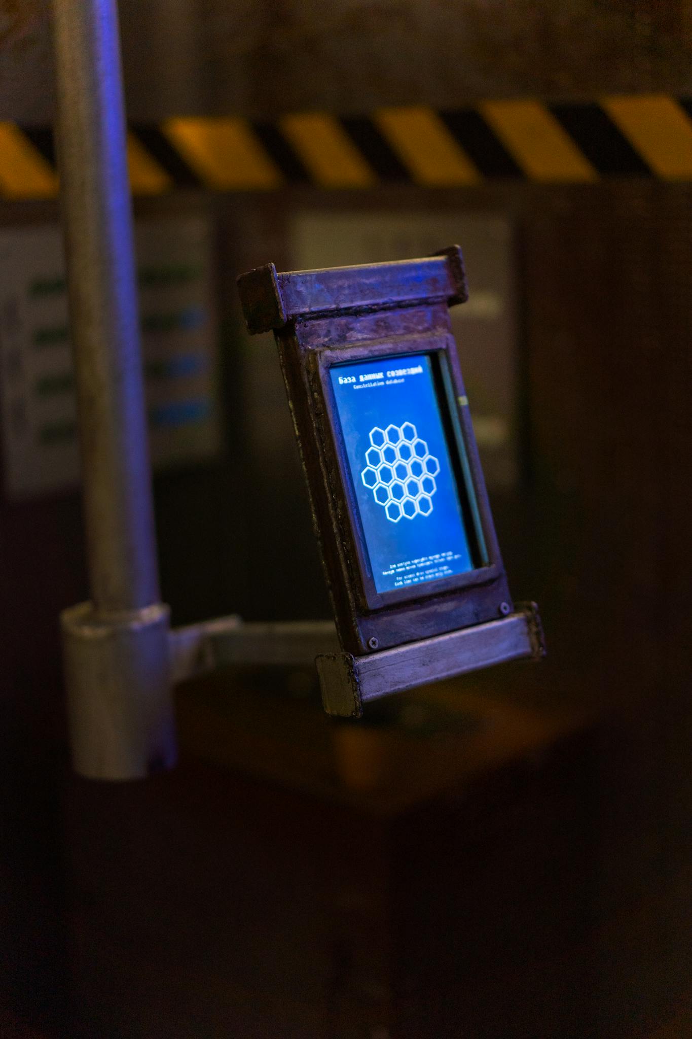 A futuristic device displaying a glowing blue interface in a dimly lit industrial environment, conveying a sci-fi theme.